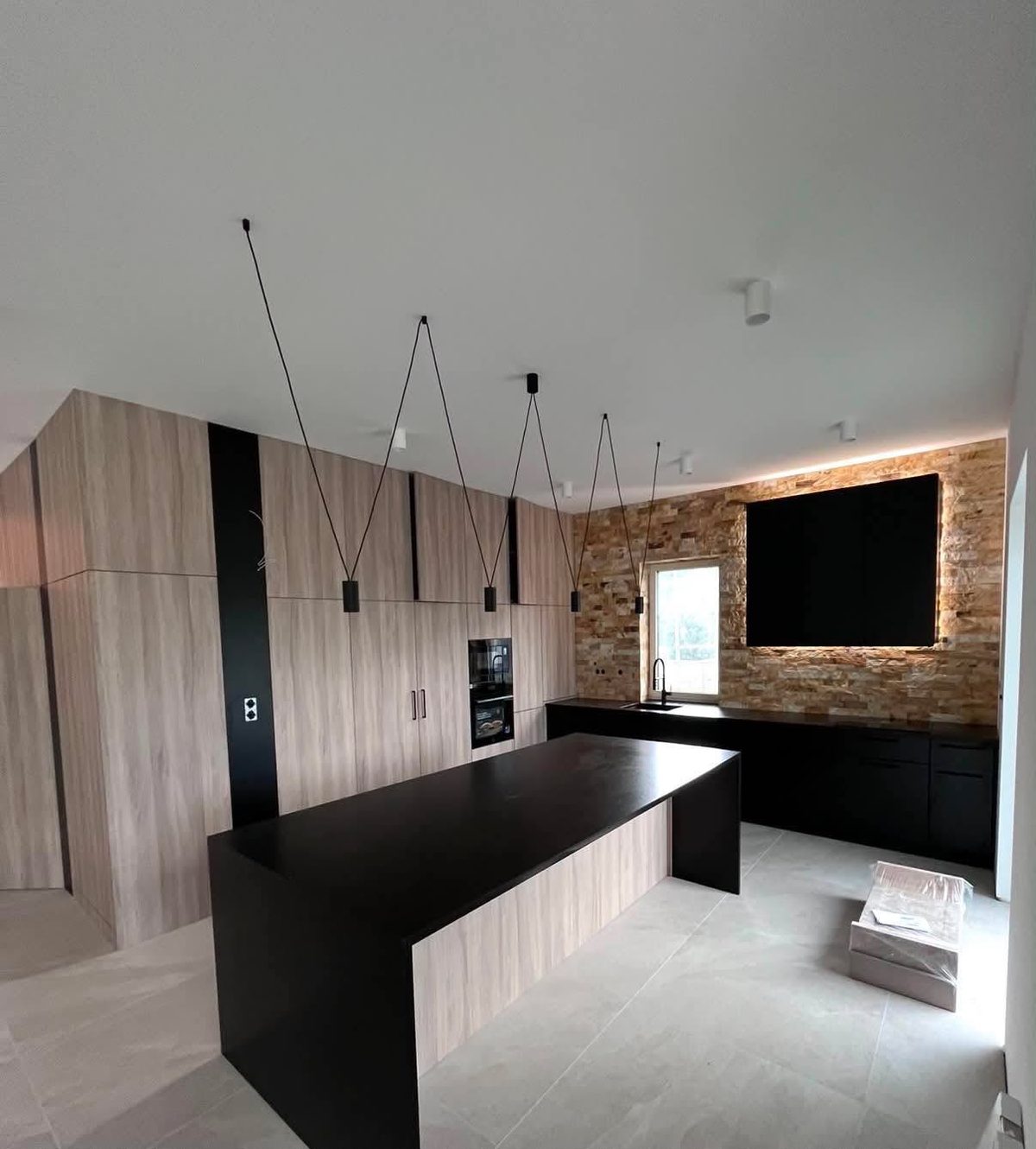 Kuchnia loftowa z czarną wyspą, drewnianymi frontami i ceglaną ścianą - realizacja Pol-Mebel